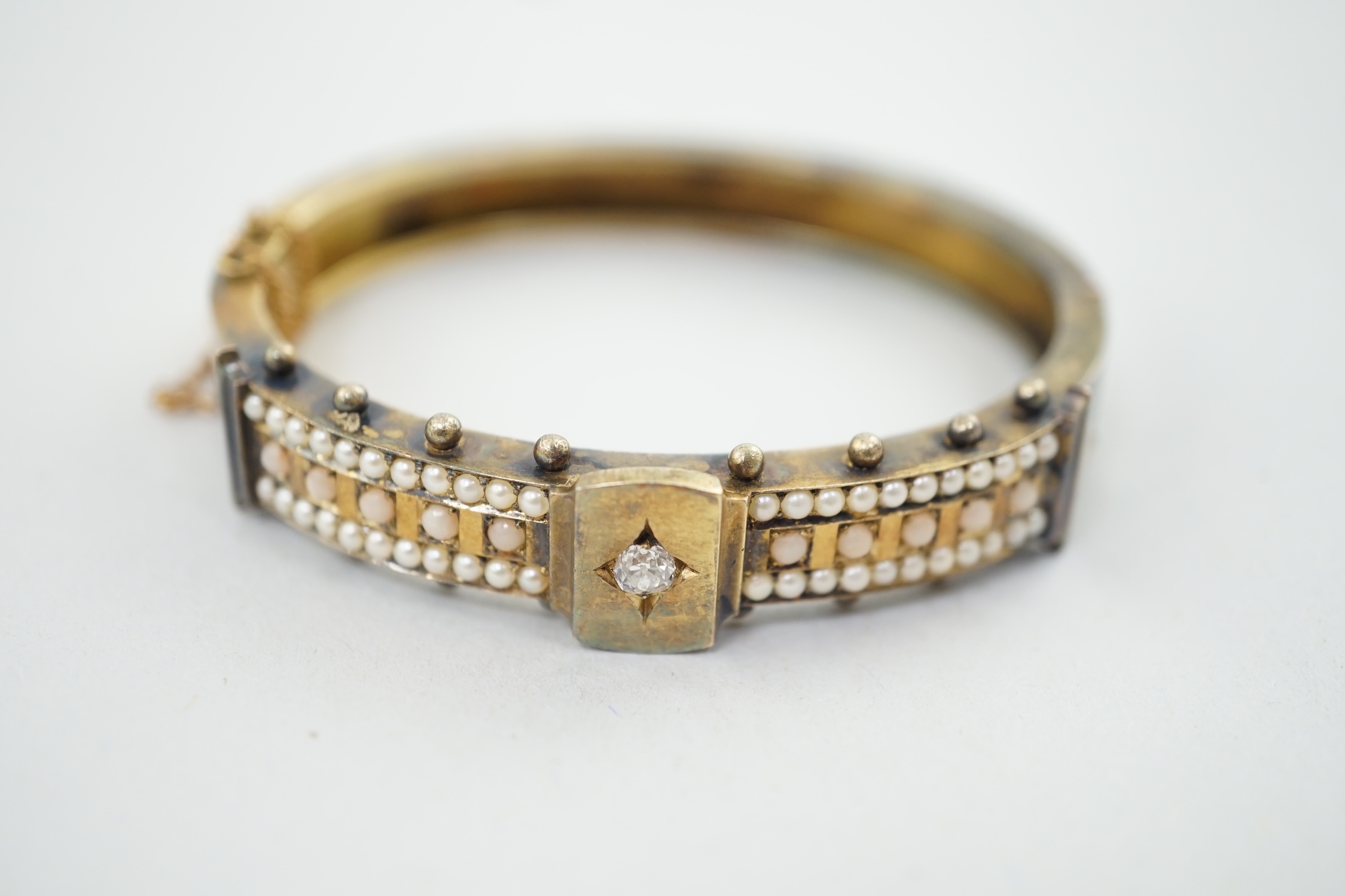 A Victorian, gold, single stone diamond and seed pearl and coral bead cluster set hinged bangle